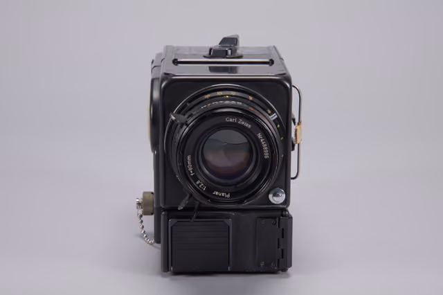 A Hasselblad 70mm camera body flown on Apollo 11, photographed against a plain background in museum lighting, its lens mount and film magazine attachment visible.