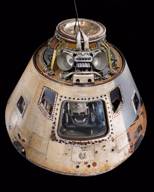 The Skylab 4 command module, a conical spacecraft with a charred heat shield, on museum display.
