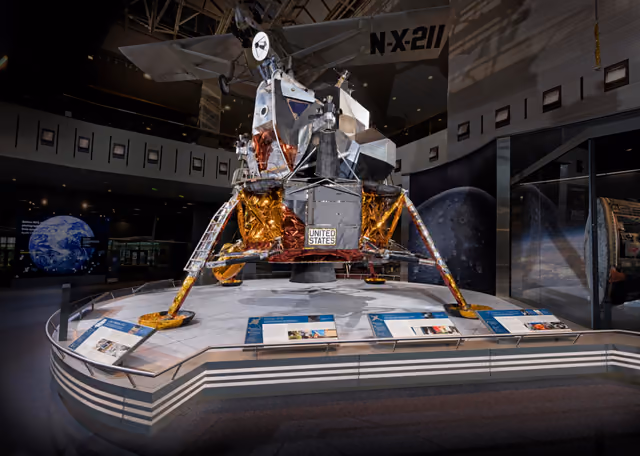 Apollo Lunar Module 2, a complete two-stage lunar lander with foil-wrapped descent stage and angular ascent stage, on display in a museum gallery.